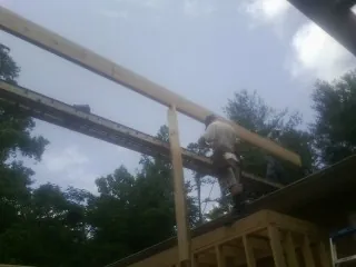 Carpenter setting a ridge beam over a new addition frame — Ice Dam Removal by Roofing Brothers in Alvord
