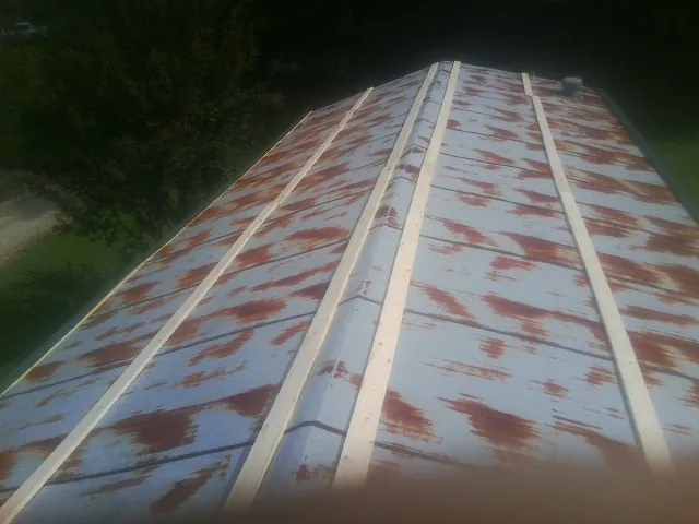 Rusted metal roof panels with new wood purlins before replacement — Storm Damage Roof Repair in Alvord by Roofing Brothers