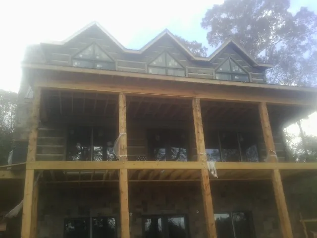 Dormers and porch framing on a large log home under construction — Roof Coating work by our crew in Alvord