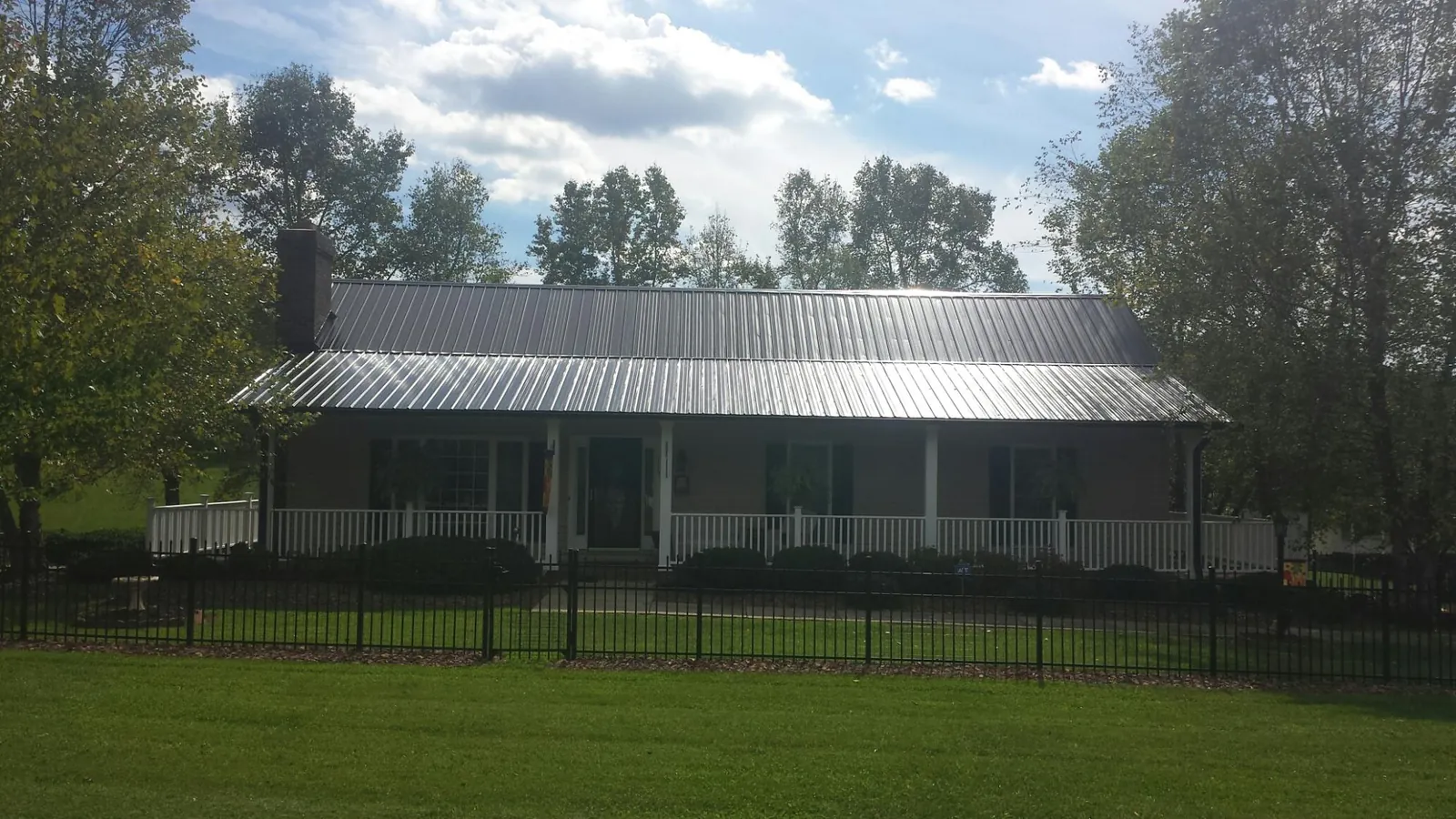 Gray metal roof on a brick ranch with a full width front porch — Gutter Guard Installation work by our crew in Alvord