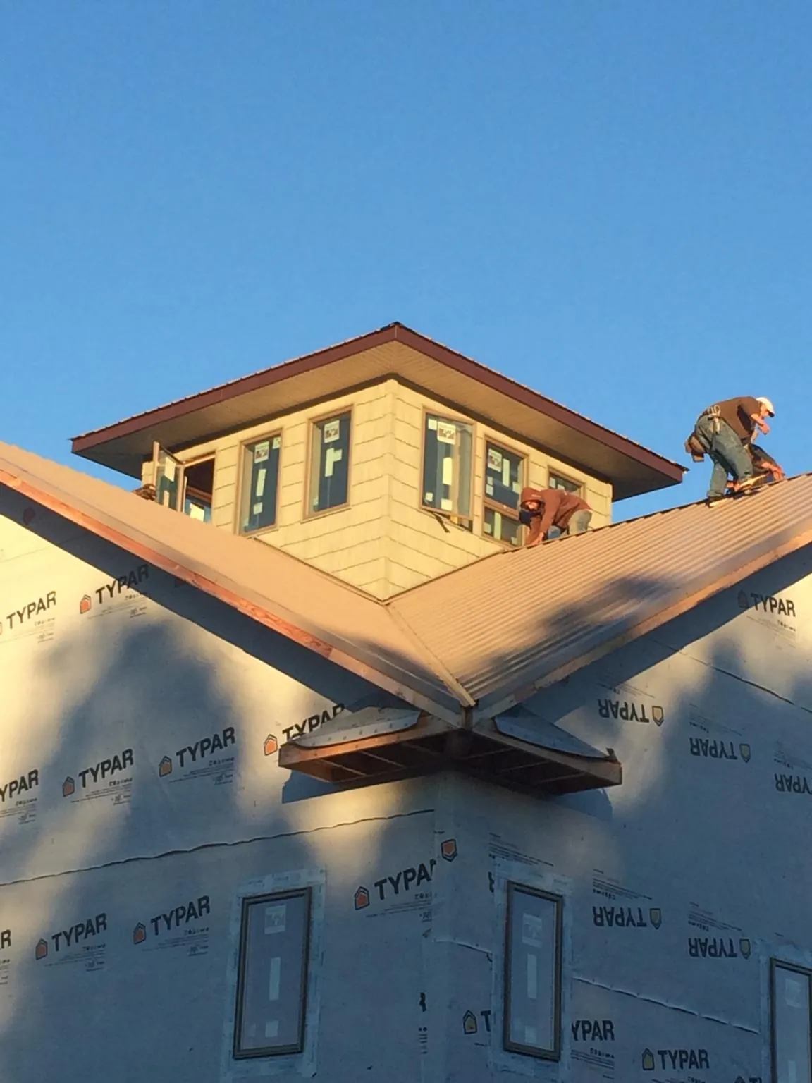 Roofers working around a rooftop cupola on a new metal roof at sunset — Roof Waterproofing in Alvord by Roofing Brothers